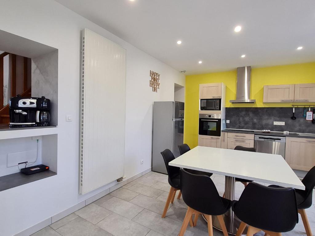 a kitchen with a white table and black chairs at Maison de charme rénovée proche Verdun, idéal randos, 3 ch, jardin, terrasse, cuisine équipée - FR-1-585-48 in Forges-sur-Meuse
