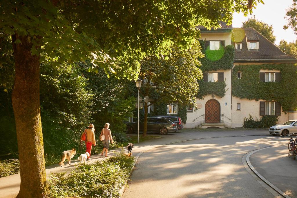 Gästehaus Englischer Garten في ميونخ: شخصان يسيران بكلبين في شارع