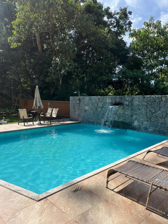 una piscina con una cascada en una pared de piedra en Apart-hotel Nova Friburgo Com café da manhã en Nova Friburgo