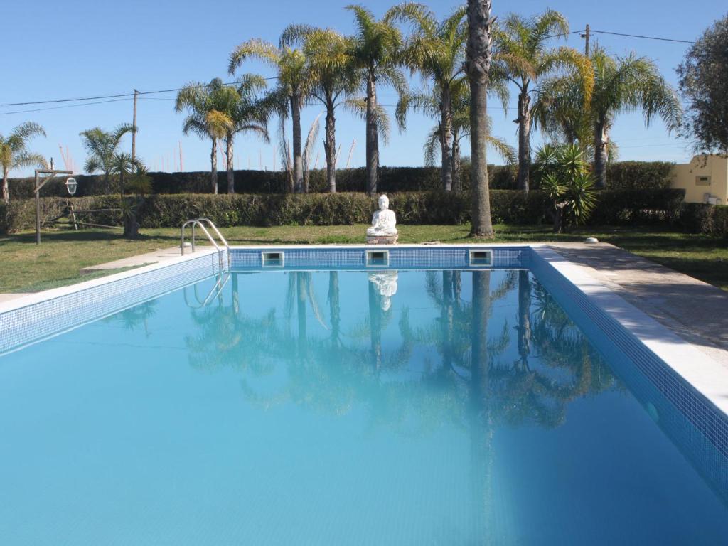 a blue swimming pool with palm trees in the background at Holiday Home Quinta Dahlia by Interhome in Pegões