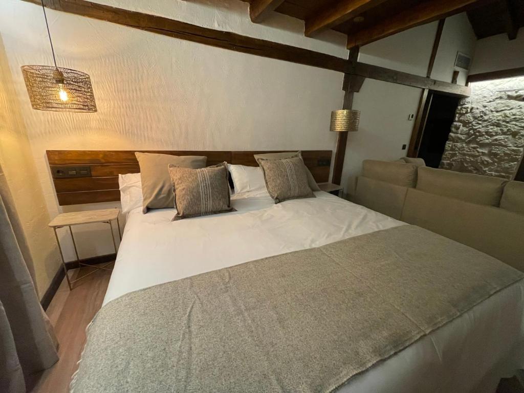 a bedroom with a large white bed and a couch at La Casa del Cantero in Pinilla del Valle