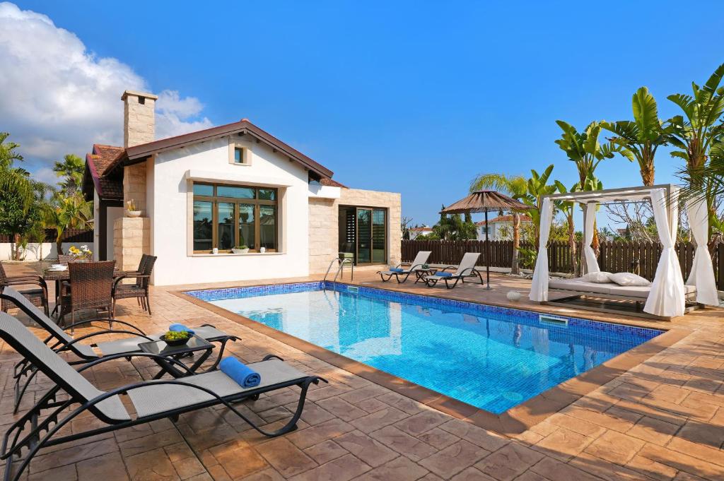 uma piscina com cadeiras e um gazebo ao lado de uma casa em Villa Lara - 3bed Bangalow with Large Pool em Agia Napa