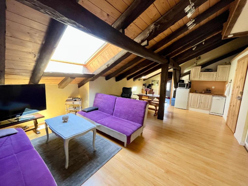ein Wohnzimmer mit einem lila Sofa und einem Tisch in der Unterkunft Charmant studio dans ferme avec terrasse et parking - montagnes des Vosges - FR-1-589-164 in Le Ménil