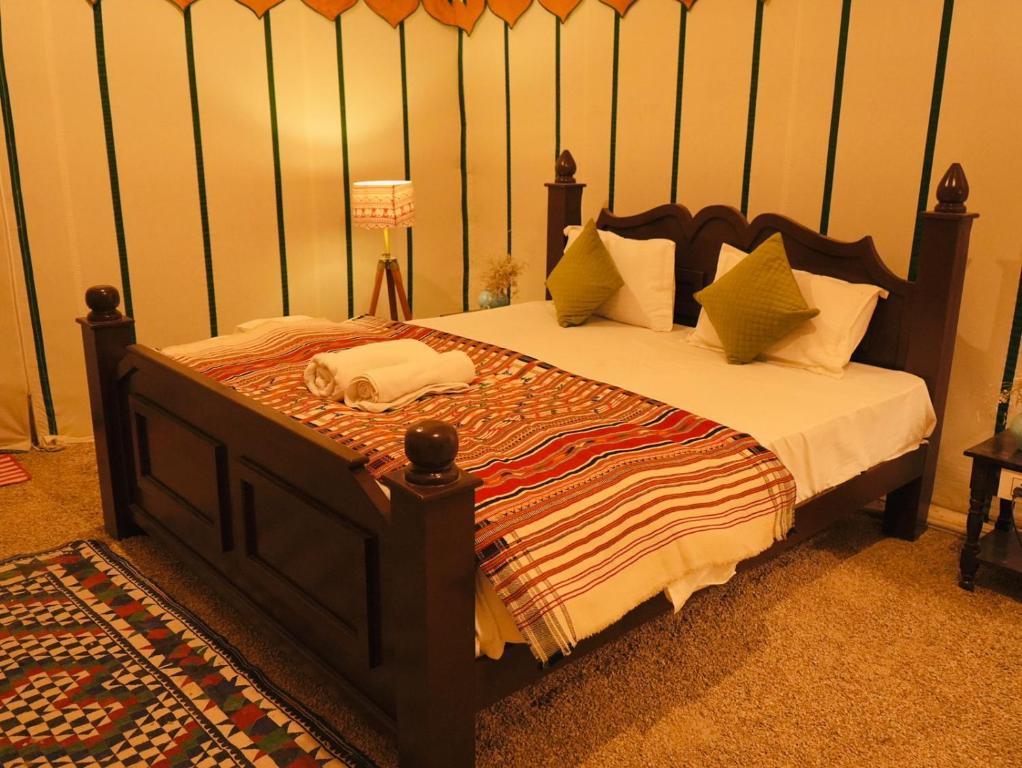 - une chambre avec un grand lit et une tête de lit en bois dans l'établissement Venture Desert Camp Jaisalmer, à Sām