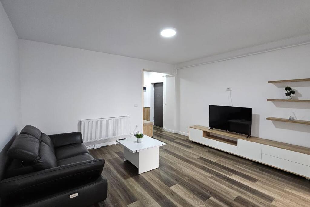 een woonkamer met een zwarte bank en een flatscreen-tv bij Nordic Residence 5 in Suceava