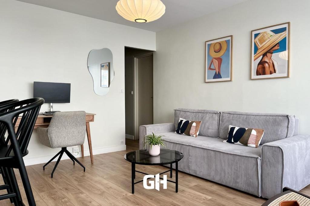 een woonkamer met een grijze bank en een bureau bij Le Silly - Bel appartement - Paris & Parc des Princes in Boulogne-Billancourt