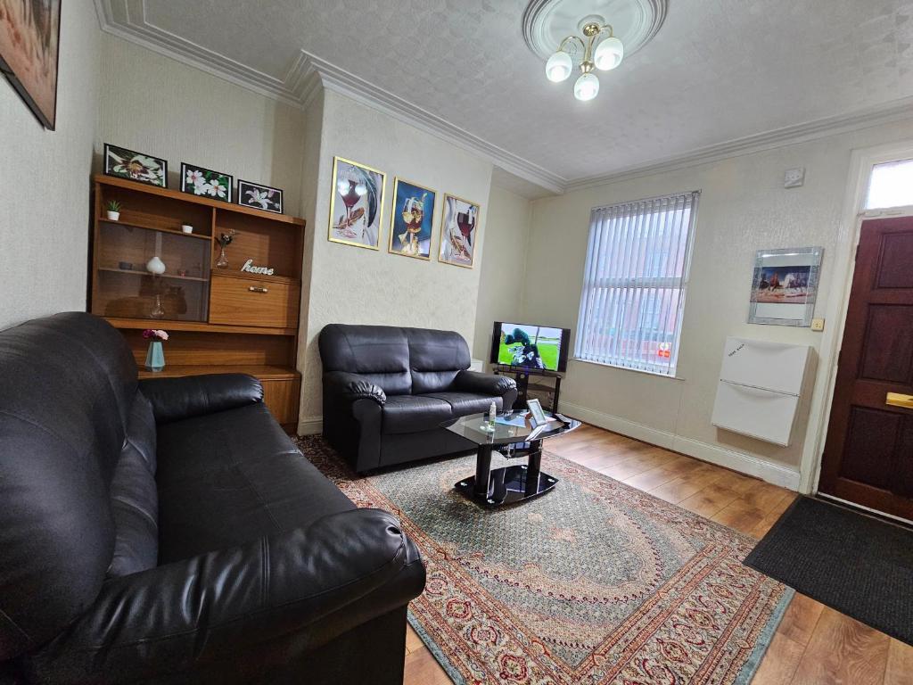 a living room with a leather couch and a table at Spacious two bedroom house, parking and WiFi in Leeds