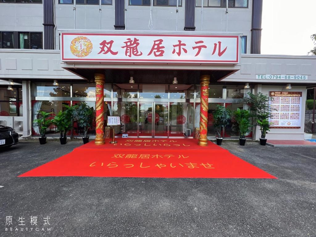 un edificio con una alfombra roja frente a un edificio en 双龍居ホテル en Miki