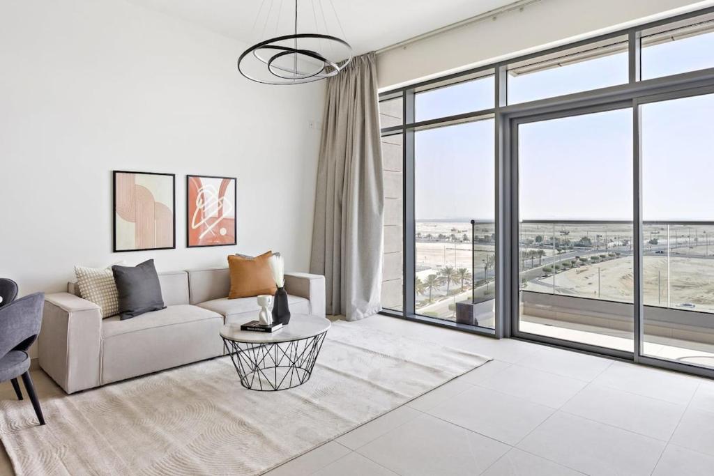 a living room with a couch and a large window at Silkhaus New 1BDR at Najmat Near Reem Central Park in Abu Dhabi