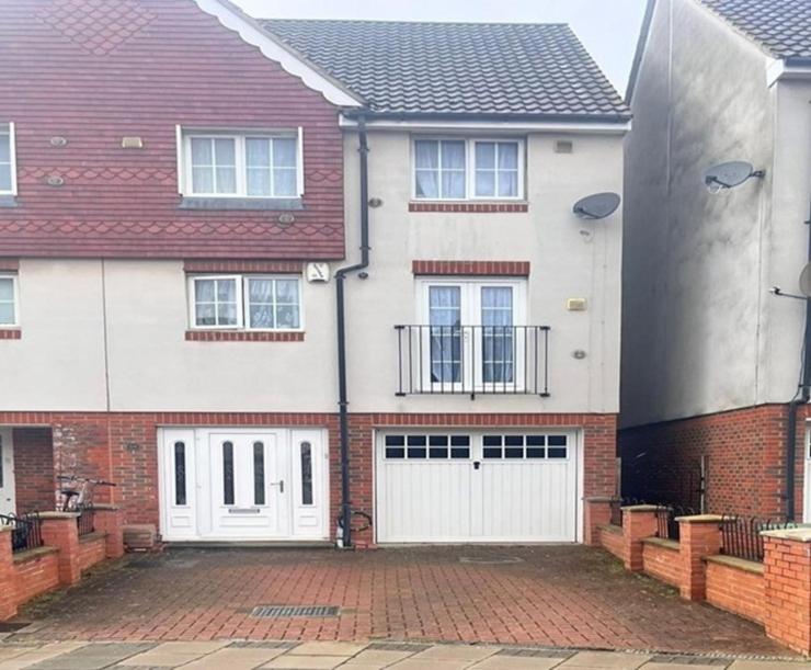 a large brick house with a white garage at Mead House in Thamesmead