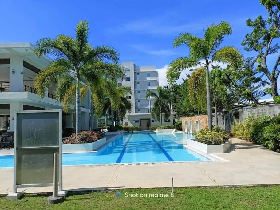 a swimming pool in front of a building with palm trees at Riz's 2BR & 1T/Bath Condo 8 Spatial Maa 3f in Davao City