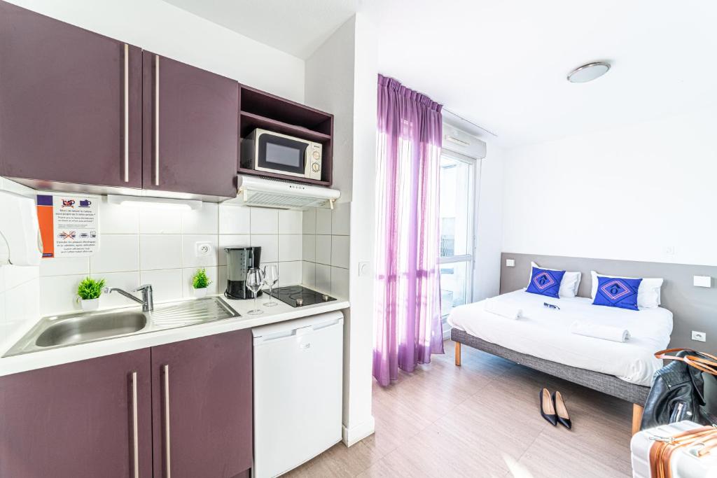 - une cuisine avec évier et un lit dans une chambre dans l'établissement Montempô Apparthôtel Marseille Centre Euromed, à Marseille