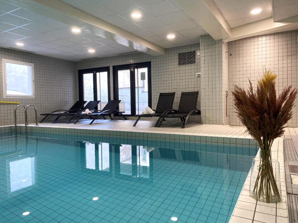 a swimming pool in a building with chairs around it at Nemea Appart Hotel Home Suite Nancy Centre in Nancy