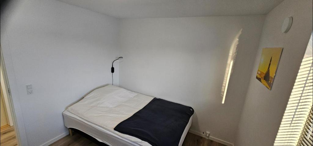 ein weißes Zimmer mit einem kleinen Bett in der Ecke in der Unterkunft Ilulissat Hostel in Ilulissat