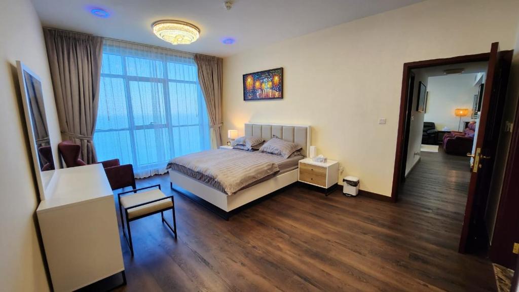 ein Schlafzimmer mit einem Bett, einem Stuhl und einem Fenster in der Unterkunft Ocean View Luxury Suites in Ajman 