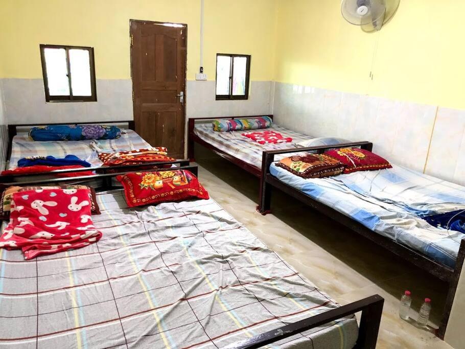 a group of three beds in a room at Countryside Schoolstay in Takeo
