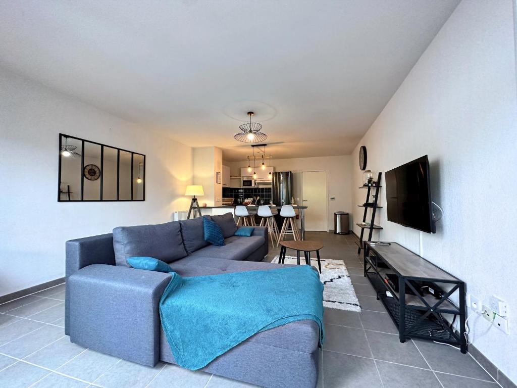 a living room with a blue couch and a kitchen at Villa lumineuse T3 - Proche Aéroport MEETT Airbus in Aussonne