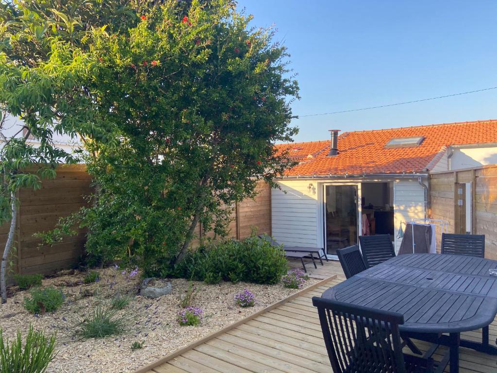 eine Terrasse mit Tisch und Stühlen auf einem Deck in der Unterkunft Maison Traditionnelle Rénovée, Proche Plage, Barbâtre - Terrasse, Wifi, Confort Modern - FR-1-426-371 in Barbâtre