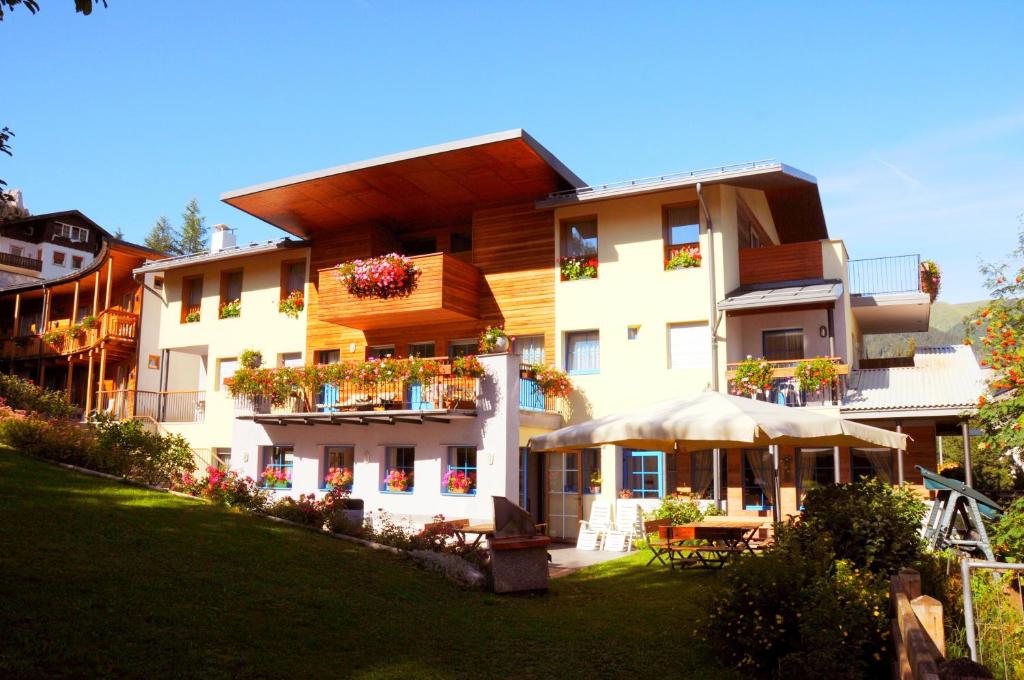 un grande edificio con piante sui balconi di Garni Enrosadira a Vigo di Fassa