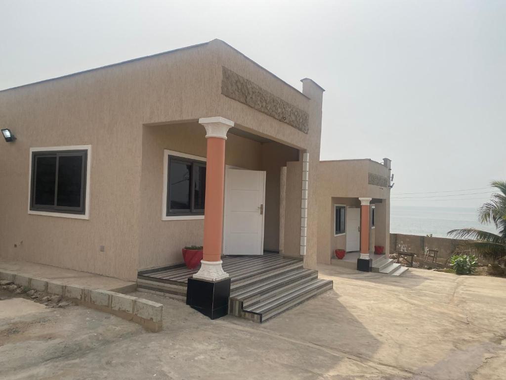 a small house with a porch and a pole at Arm Beach Lodge in Accra