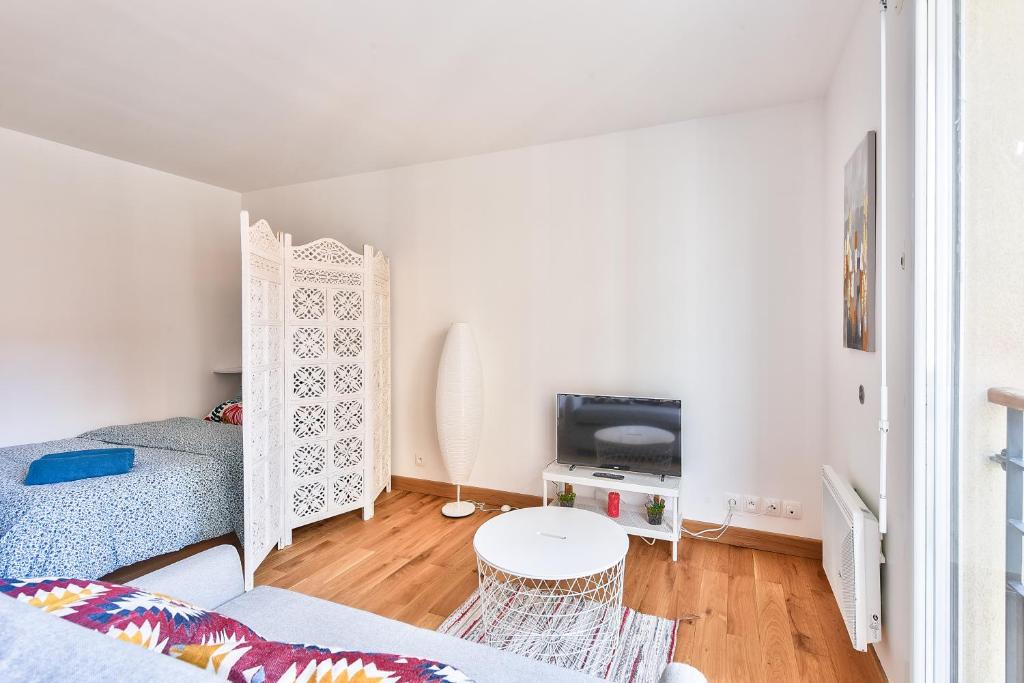een witte slaapkamer met een bed en een tafel bij Budget studio with parking - The river seine in Saint-Denis