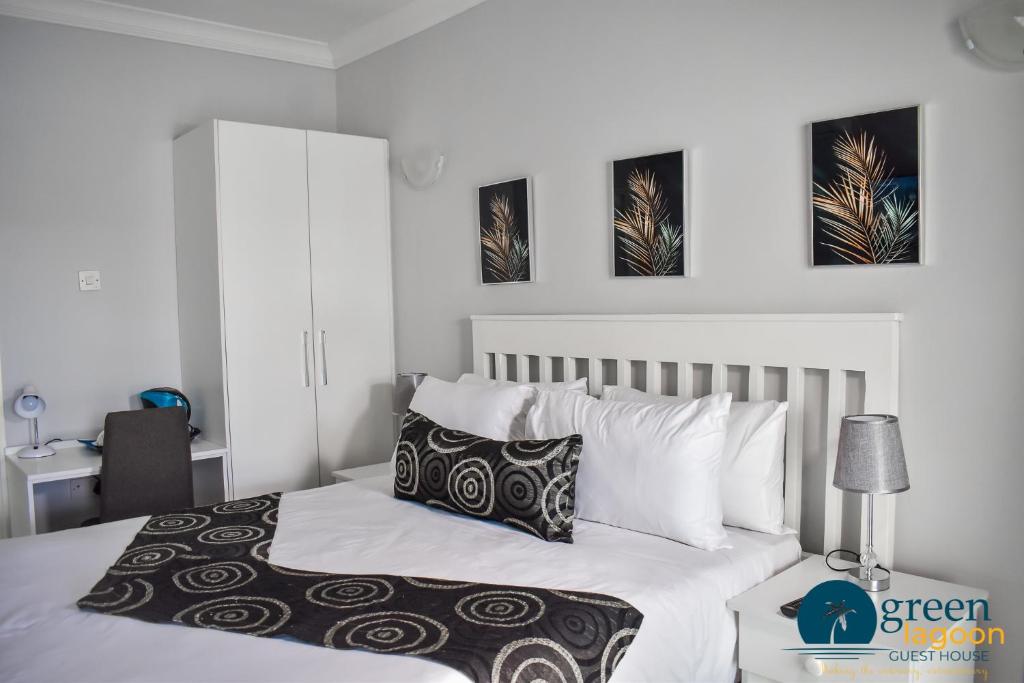 a bedroom with a bed with white sheets and pillows at Green Lagoon Guest House Phase 4 Branch in Gaborone
