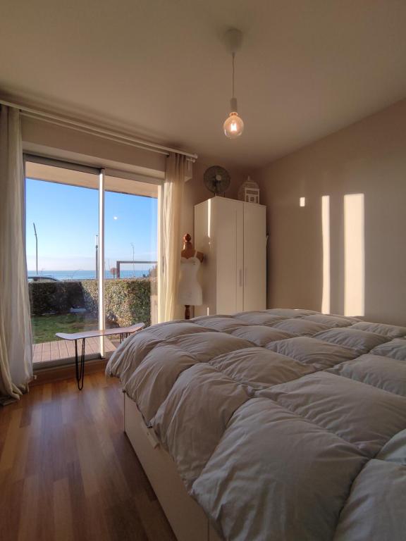 サン・ミシェル・シェフ・シェフにあるIdéal en amoureux, vue mer et jardin ! Appartement lumineux à Tharon-Plageの大きなベッドと大きな窓のある寝室