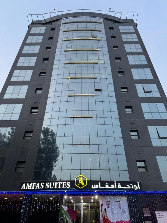 a tall building with an americas suites sign on it at Amfas Suites اجنحة امفاس in Manama