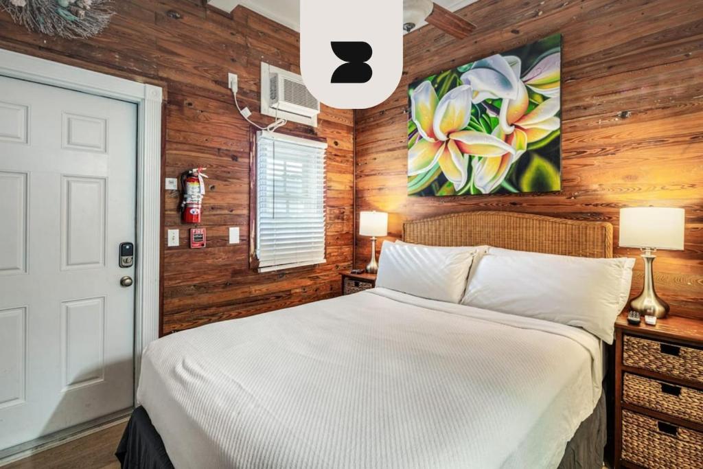 a bedroom with a white bed and wooden walls at Coral Cove #1 by Brightwild in Key West