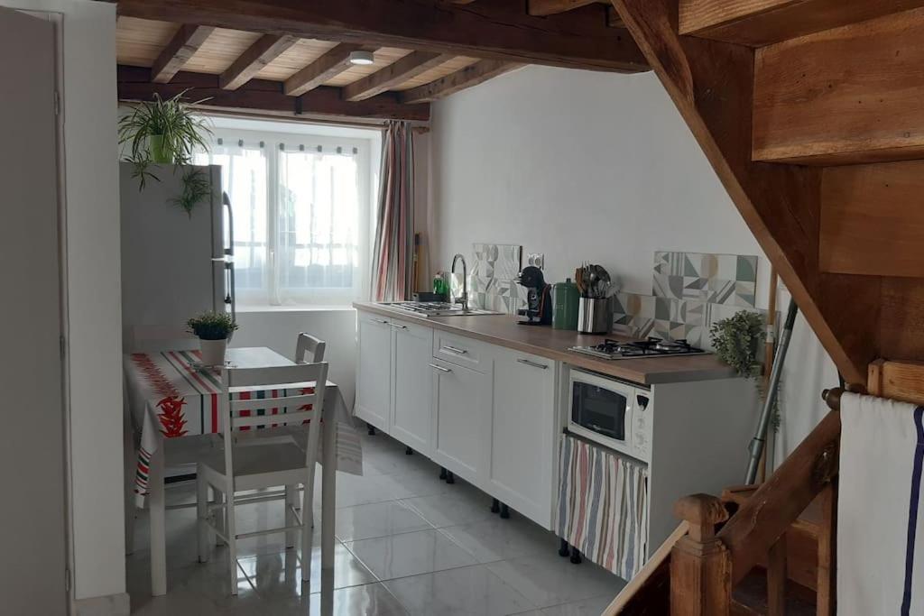 uma cozinha com armários brancos e uma mesa e uma mesa e cadeiras em Maison de campagne em Issor