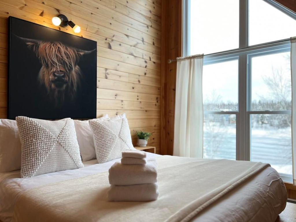 1 dormitorio con 1 cama con una foto de una vaca en la pared en Chalet Le Huard, en Weedon-Centre