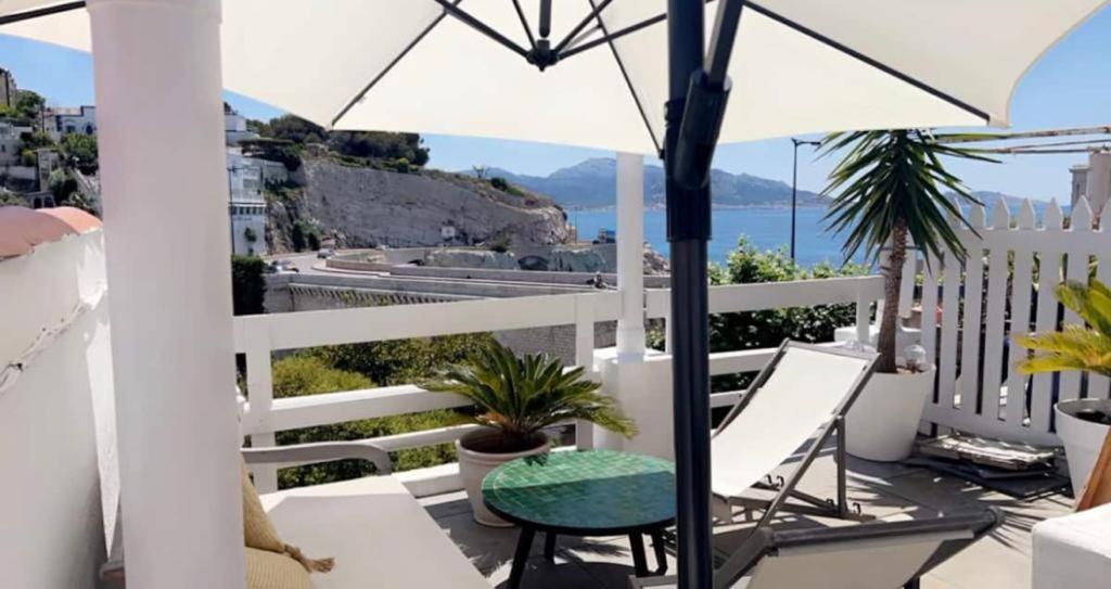 un balcon avec une table, des chaises et un parasol dans l'établissement CABANA DEL MAR, à Marseille