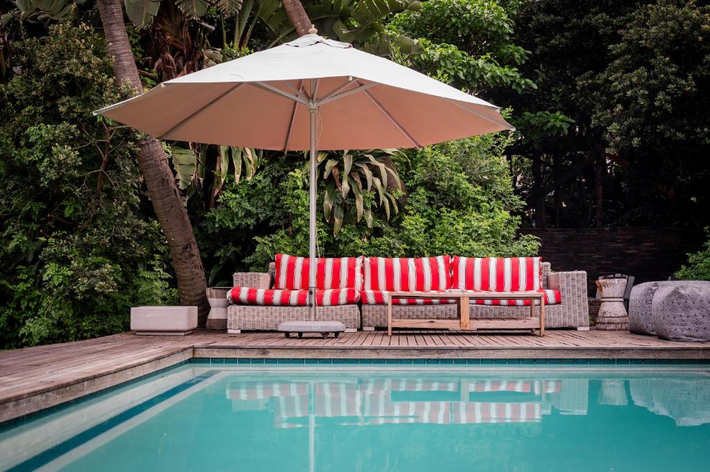 una sombrilla y dos sillas rojas y blancas junto a una piscina en Luxury Private Beach Villa centrally located. en Westbrook