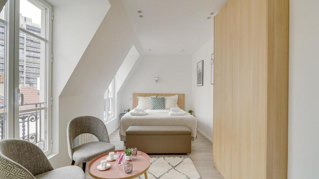 um quarto com uma cama, 2 cadeiras e uma mesa em 162 Suite Benjamin - Superb apartment in Paris em Paris