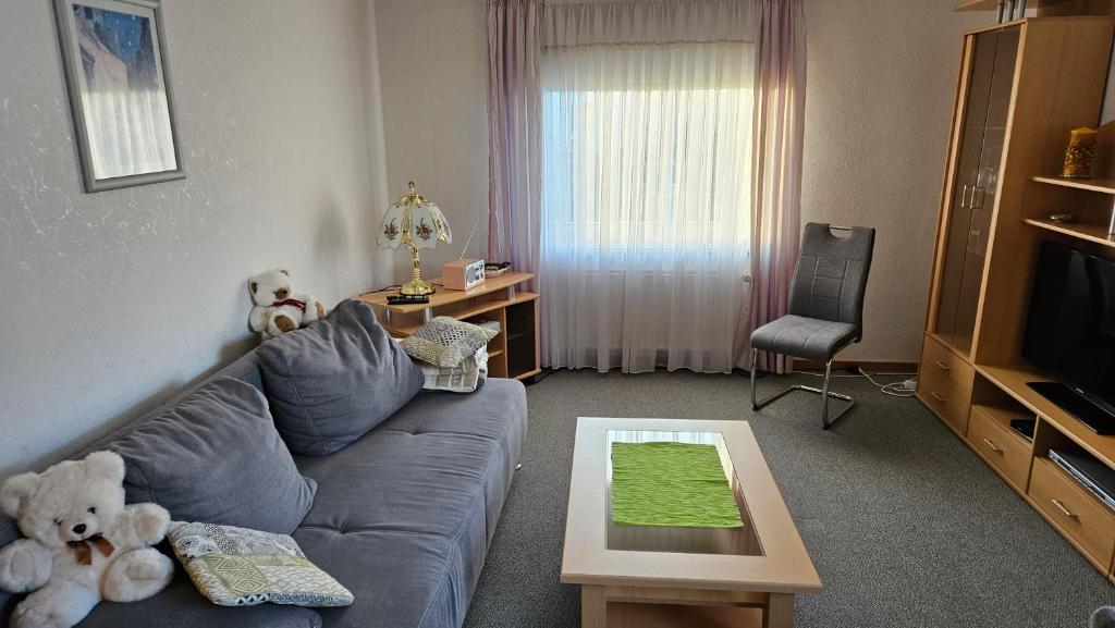 Carmen's Ferienwohnung في Apelern: غرفة معيشة مع أريكة زرقاء و دببة