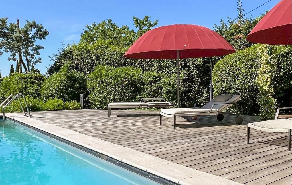 una terraza con 2 sillas y una sombrilla roja junto a la piscina en Lovely Home In Lussan With Outdoor Swimming Pool, en Lussan