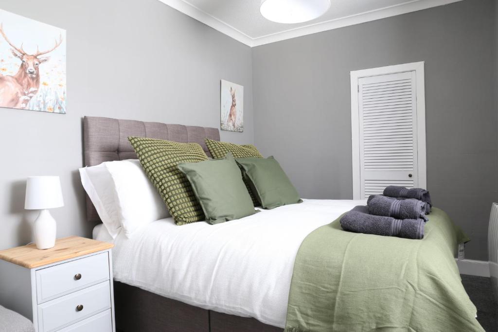een slaapkamer met een groot wit bed met groene kussens bij Bank Place in Crieff