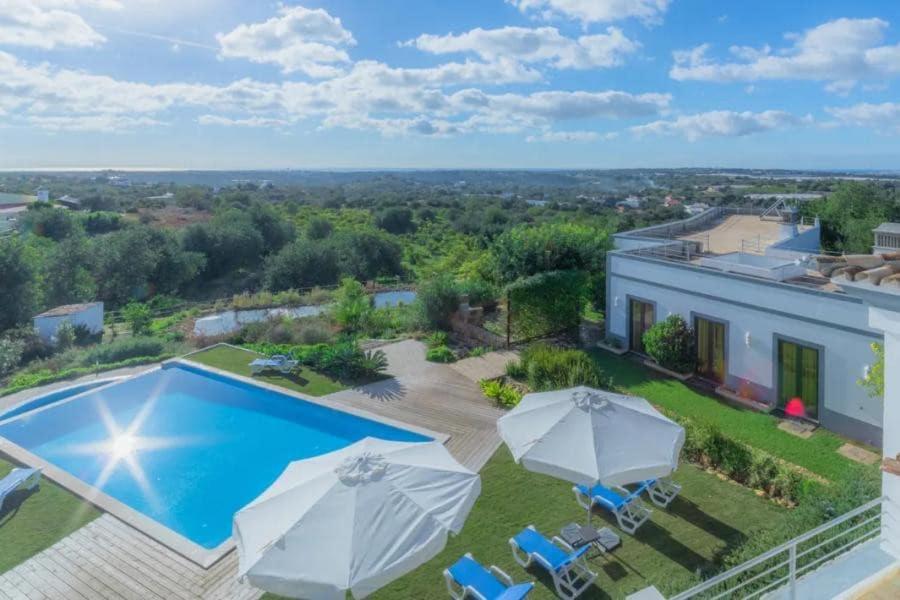 an aerial view of a house with a swimming pool and umbrellas at Villa Areias I - Beautiful landscape garden in Estói