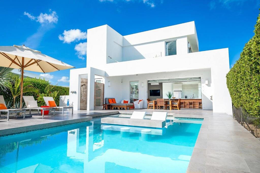 eine Villa mit einem Pool vor einem Haus in der Unterkunft Oceanside 2 Bedroom Luxury Villa with Private Pool, 500ft from Long Bay Beach -V3 in Providenciales