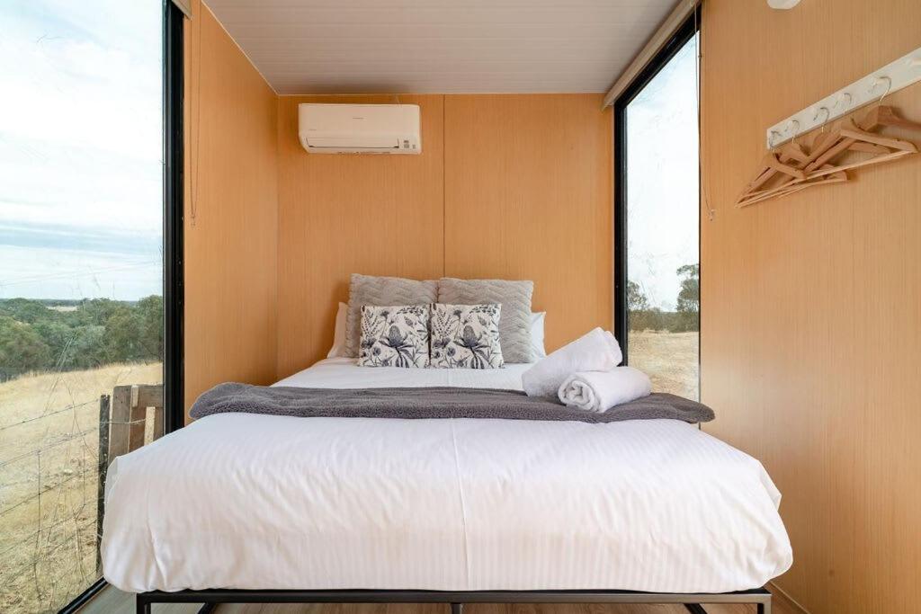 a bed in a room with a large window at Hill View at Euroa Glamping in Euroa