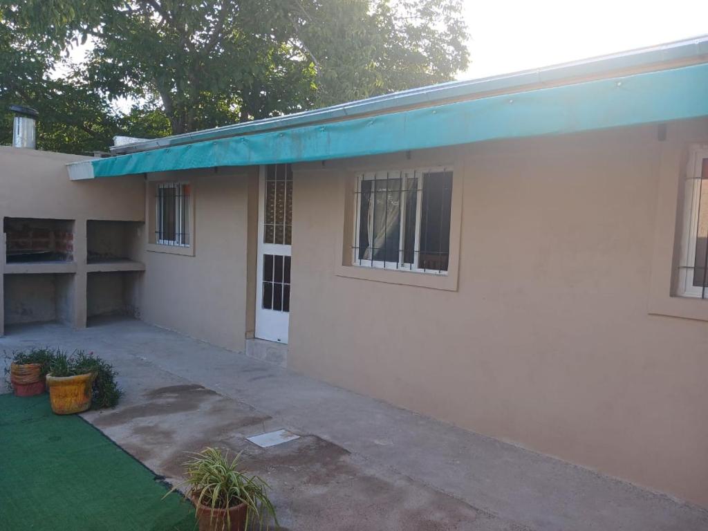 a white house with a blue awning on it at Cabaña Villa del Dique in Villa del Dique