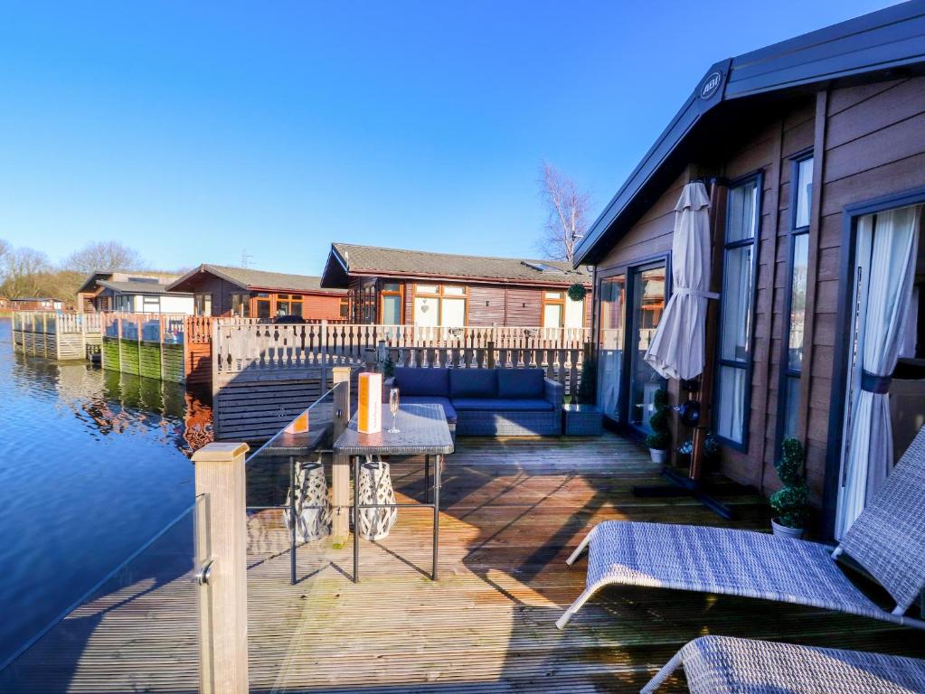 a deck with a table and chairs next to the water at Gressingham 7 in Carnforth