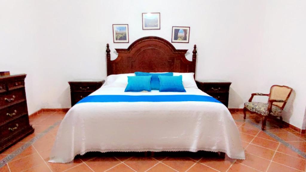 ein Schlafzimmer mit einem großen Bett mit blauen Kissen in der Unterkunft Hacienda de Comodejé in Huichapan