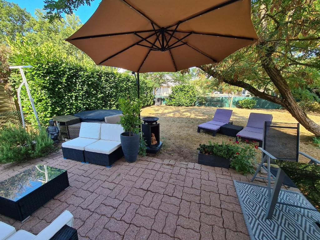 a patio with an umbrella and chairs and a fire place at Gîte tout confort avec jacuzzi, proche Loire et forêt d'Orléans, idéal pour séjours nature et détente - FR-1-590-253 in Ouzouer-sur-Loire