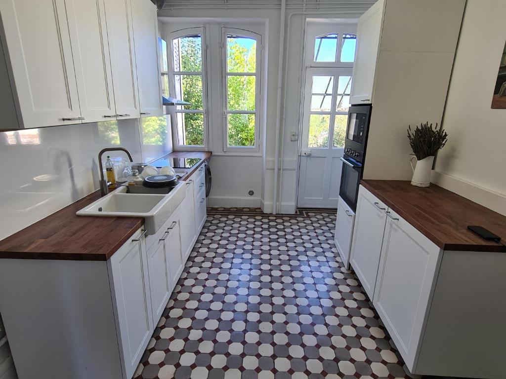 a kitchen with white cabinets and a checkered floor at Gîte Bonny-sur-Loire, 5 pièces, 8 personnes - FR-1-590-261 in Bonny-sur-Loire