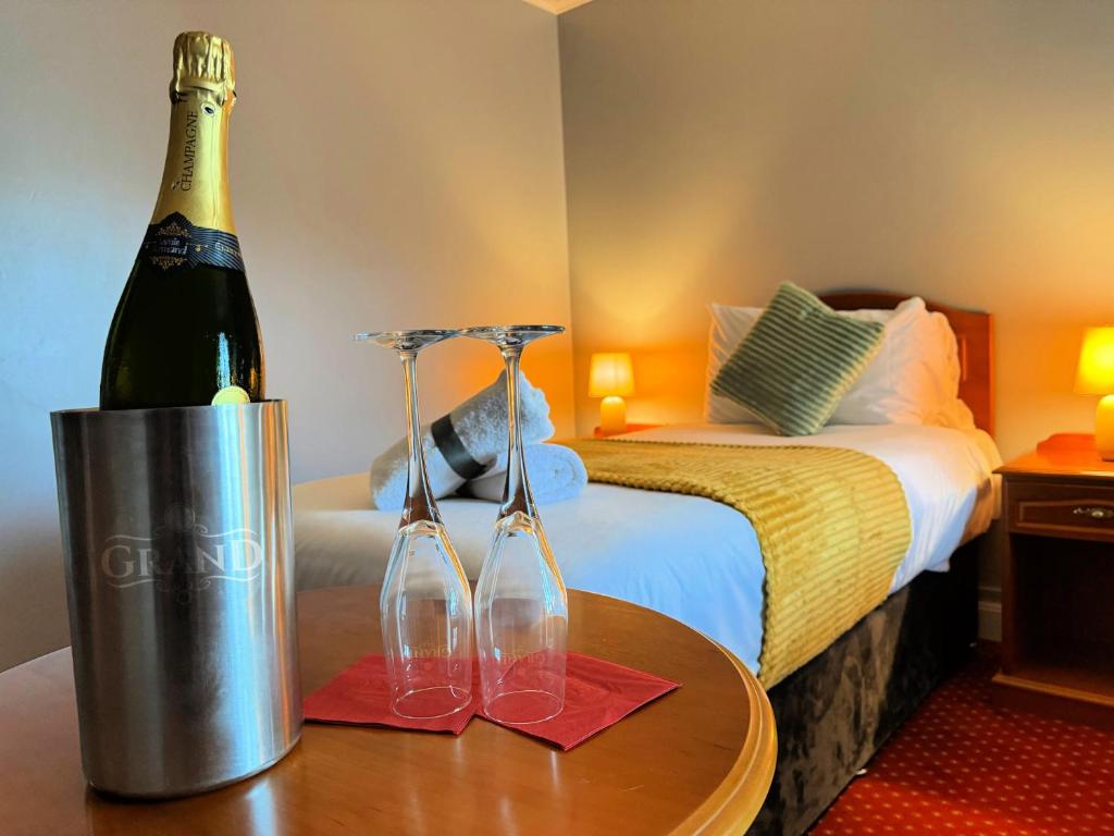 Habitación con cama y una botella de vino en una mesa en The Killarney Grand, en Killarney