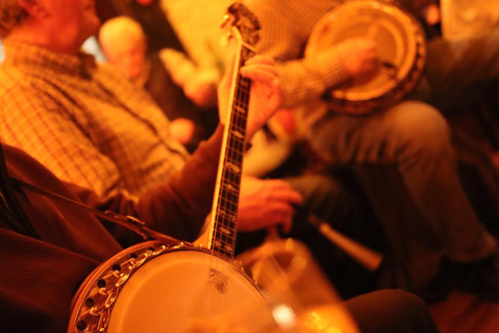 un grupo de personas escuchando a un hombre tocando una guitarra en The Killarney Grand, en Killarney