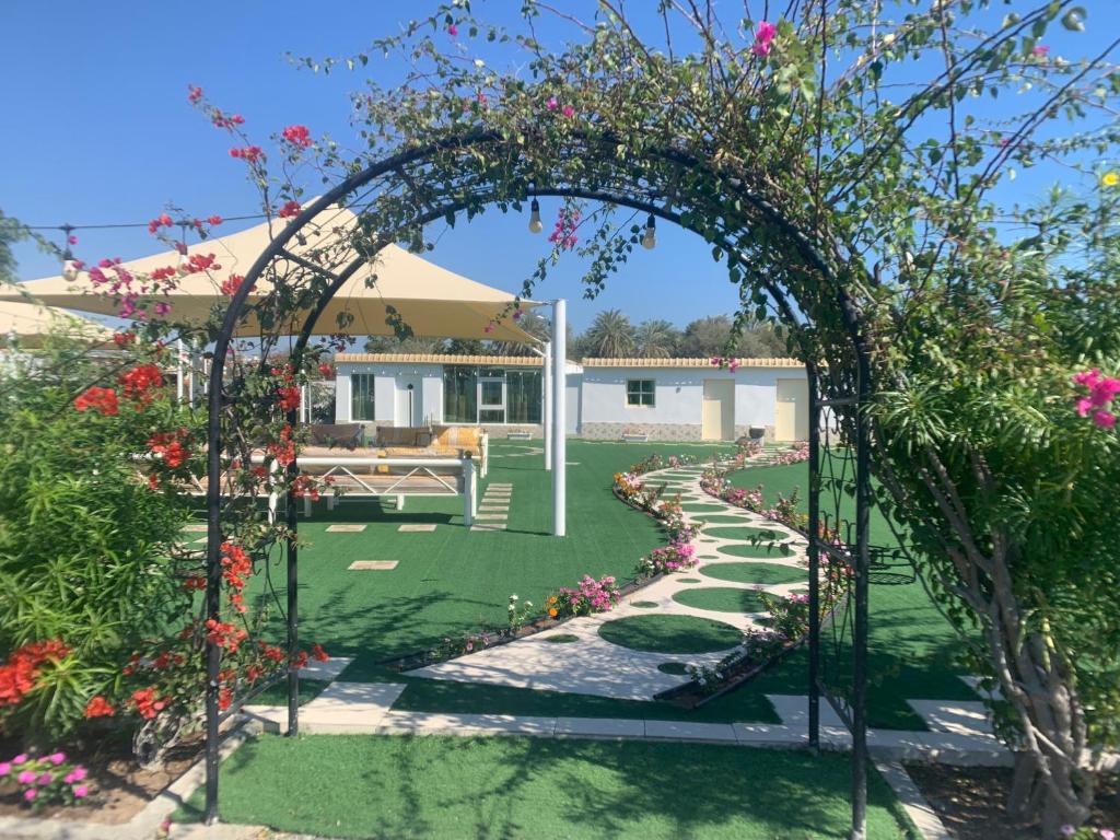 - un jardin avec une arche et des fleurs dans la cour dans l'établissement Noor Farm Stay 5BHK, à Khor Fakkan