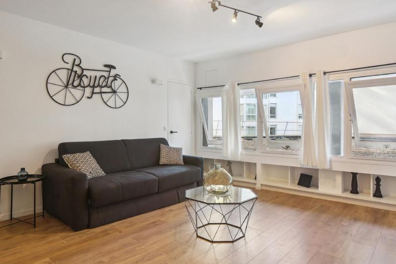 un soggiorno con divano e una bicicletta appesa al muro di 199 Suite Monopoly - Superb Apartment in Paris a Parigi