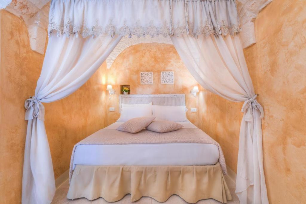 1 dormitorio con cama blanca y cortinas en Casa vinci, en Locorotondo